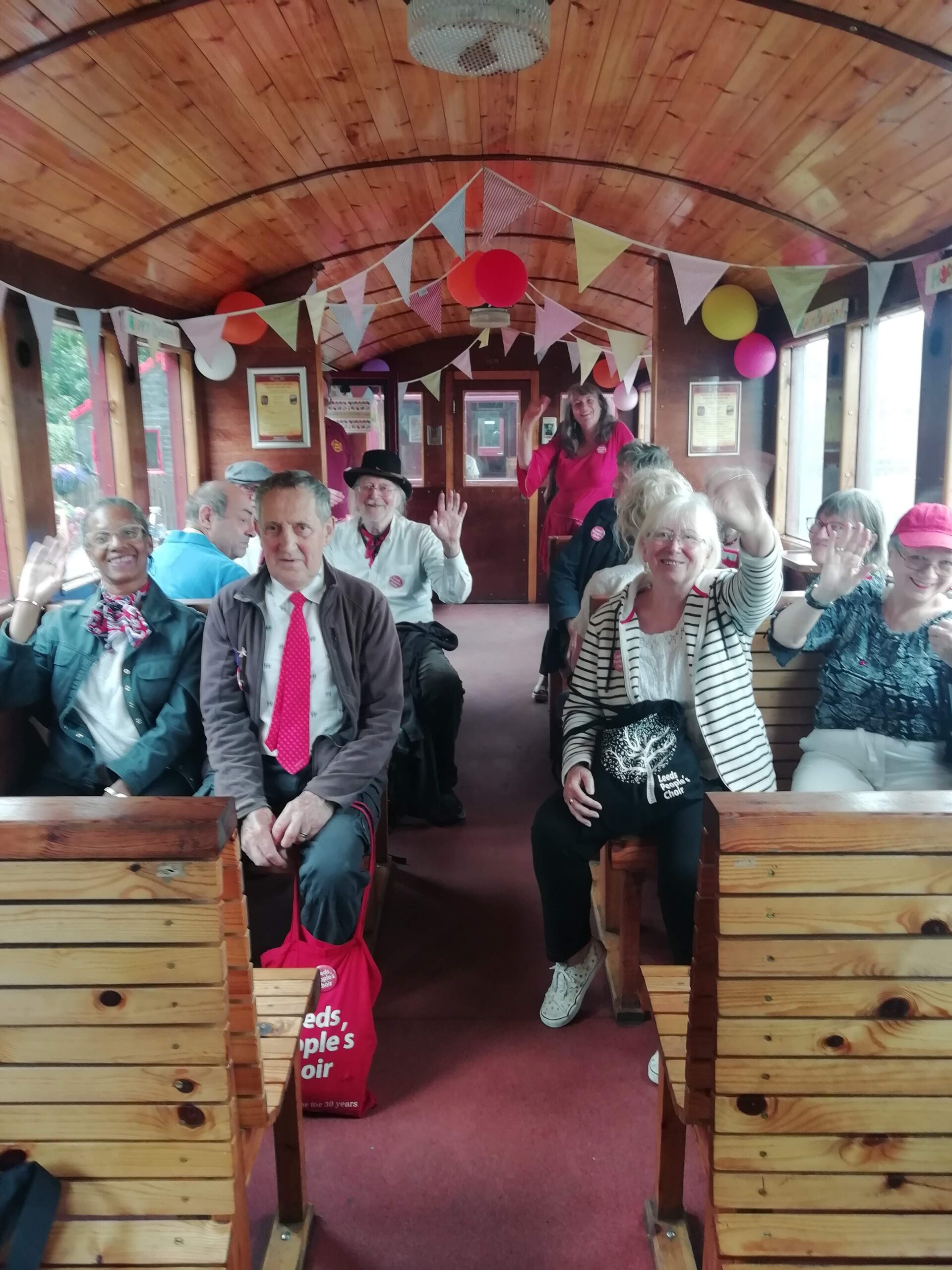 Members of Leeds People's choir looking happy on a steam train and the Middleton Railway